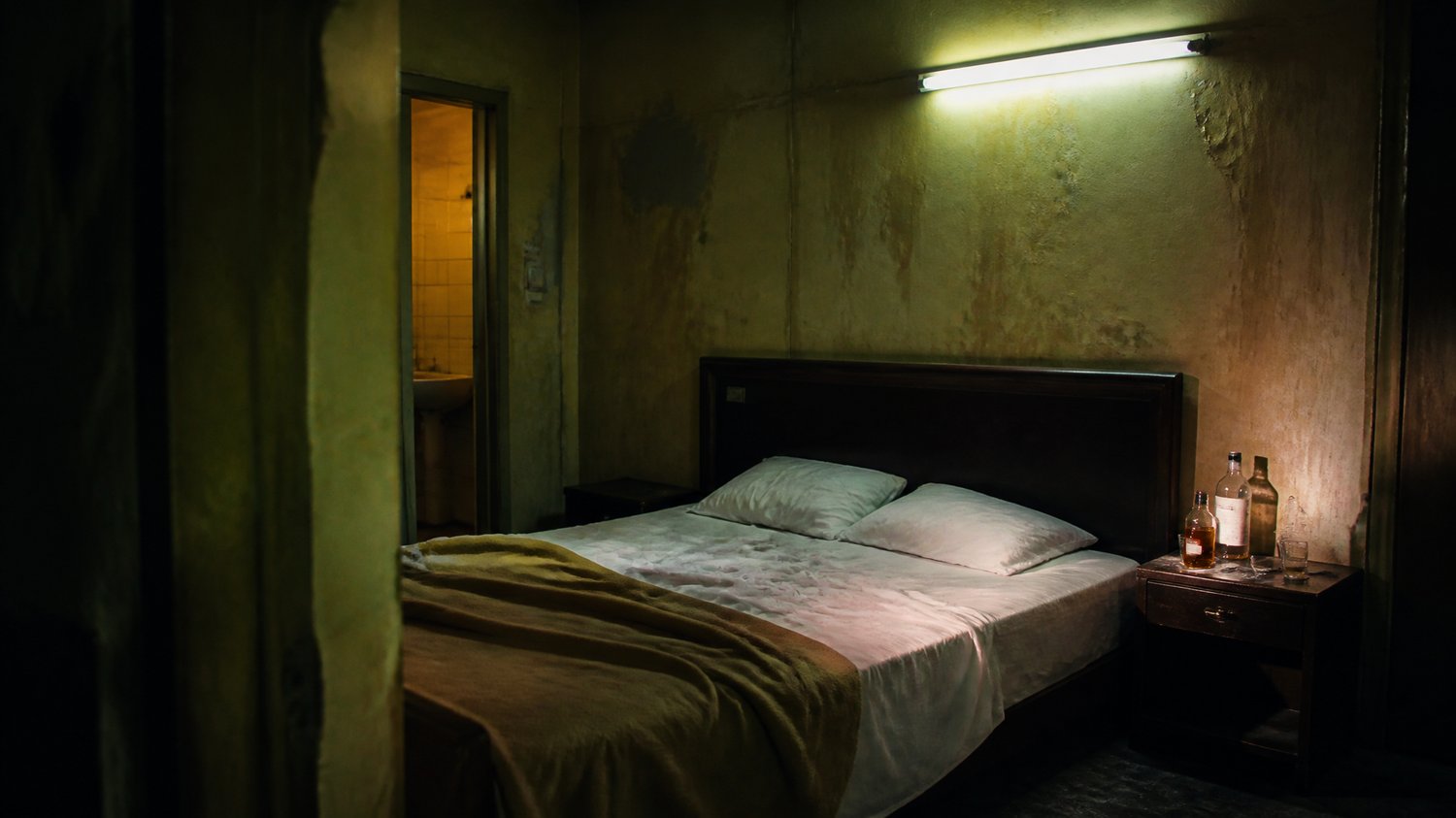 Adventure Motel — A cheap hourly motel: peeling paint, a buzzing tube-light, a sagging bed, a whisky bottle, no CCTV — chosen for exactly that. Where the ritual unfolds.