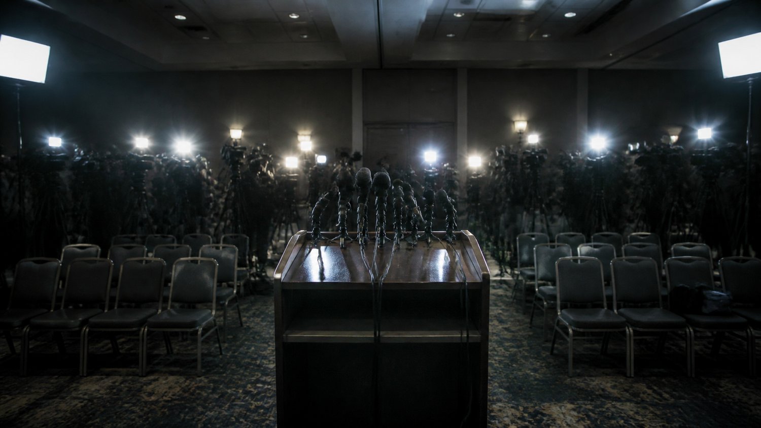 The Press Conference — The media glare that haunts every move — the case lived out in public, under flashbulbs.