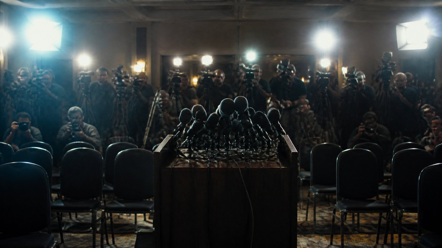 The Press Conference — The media glare that haunts every move — the case lived out in public, under flashbulbs.