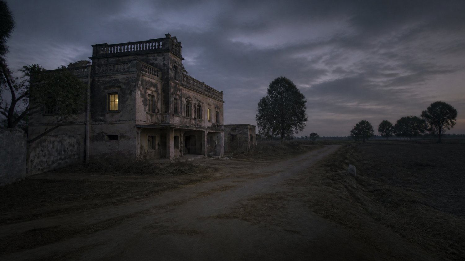 Rajjo Sadan (Exterior) — A crumbling ancestral village house off the GT Road — dust, dry fields, a siege at dusk. Where Satpal ends.